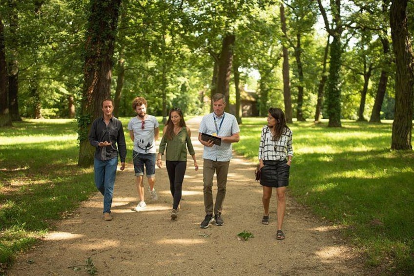 A group of people walking on a dirt path in a park with trees. 4
