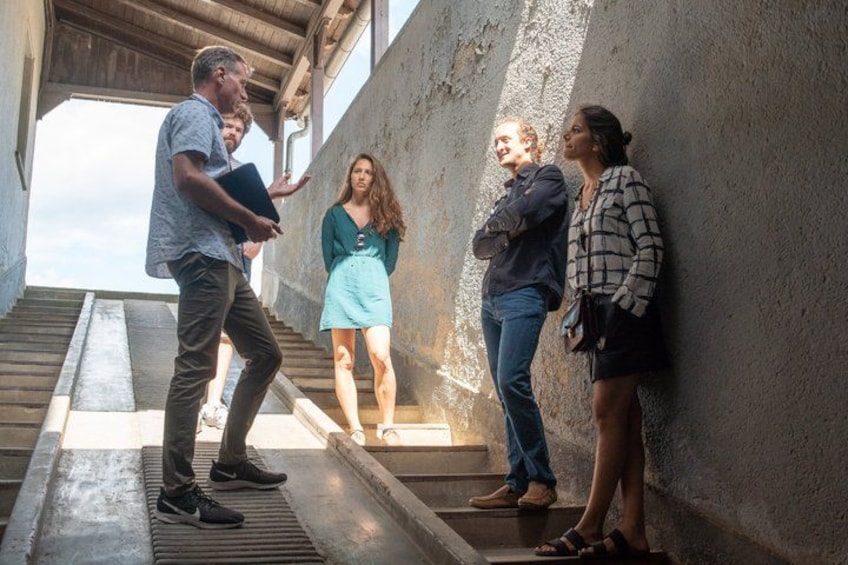 A group of people on a staircase with a concrete wall and a wooden structure overhead. 2