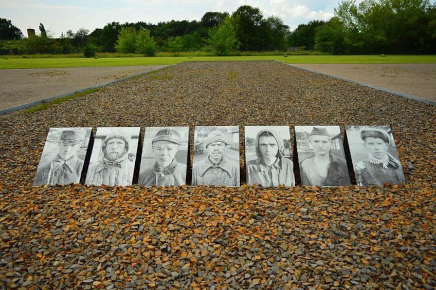 A gravel path with five black and white portraits of individuals. 3