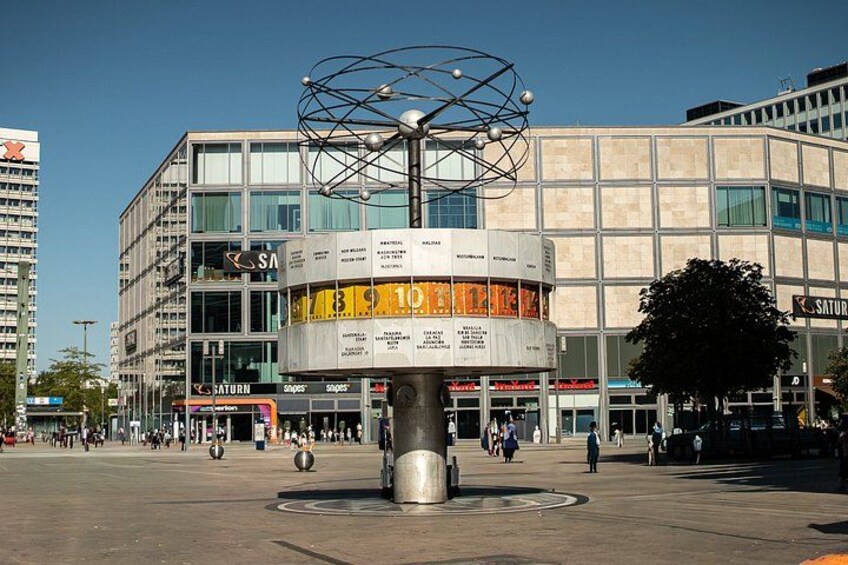 A modern plaza with a central sculpture, surrounded by multi-story buildings with commercial signage. 4