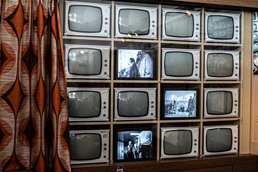 A wall of vintage televisions displaying various scenes. 3
