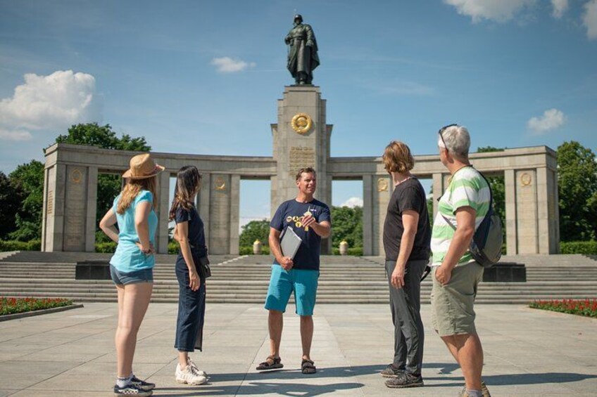A group of people standing in front of a monument with a statue. 2