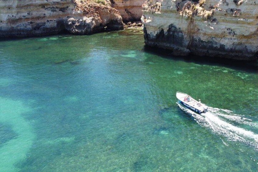 A boat on clear turquoise water near rocky cliffs. 3