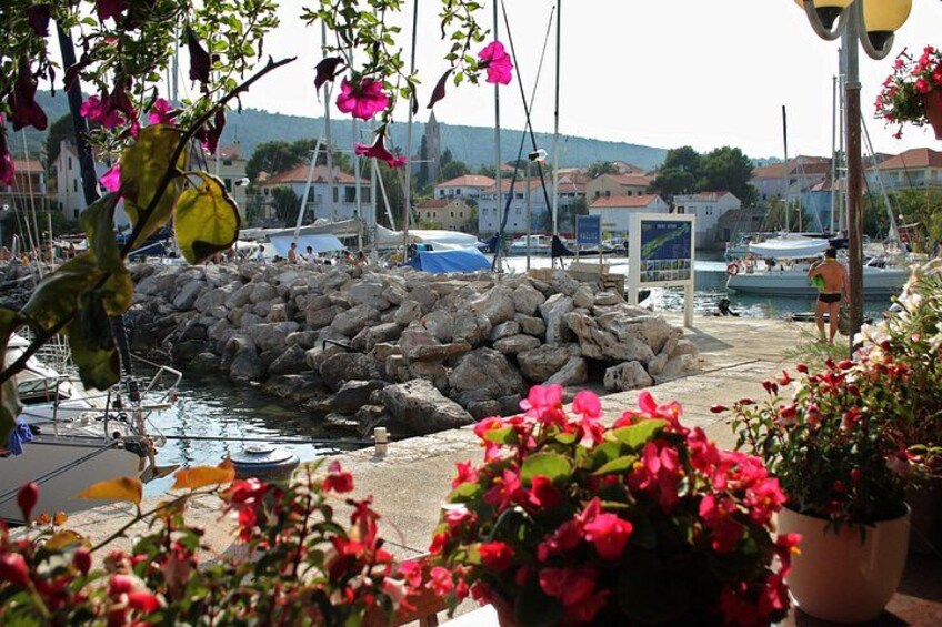 Een jachthaven met boten, een rotsenrij en bloemen in potten. 2