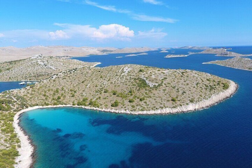 A coastal landscape with a crescent-shaped island surrounded by turquoise waters. 5