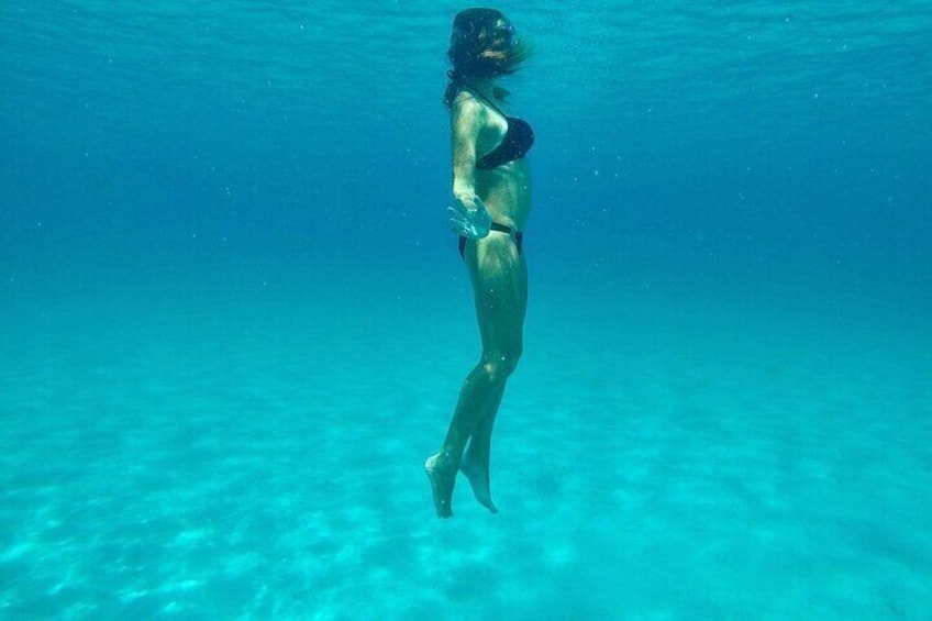 A person swimming underwater in clear blue water. 2