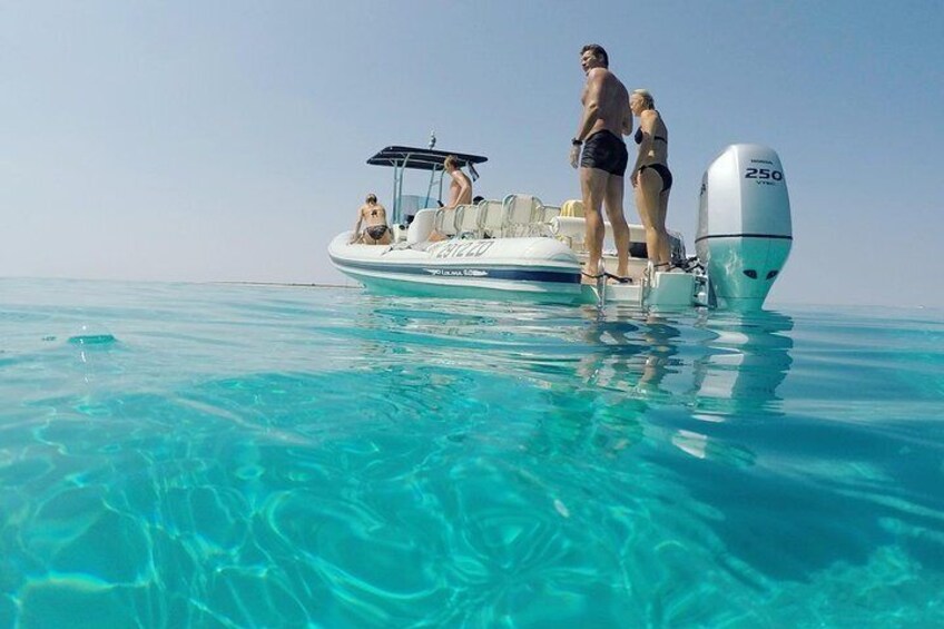 A boat with people on a clear blue sea. 3