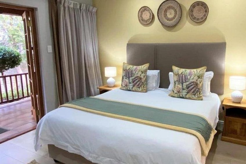 A neatly made bed with floral pillows, a bedside lamp, and a wall with decorative plates. 5