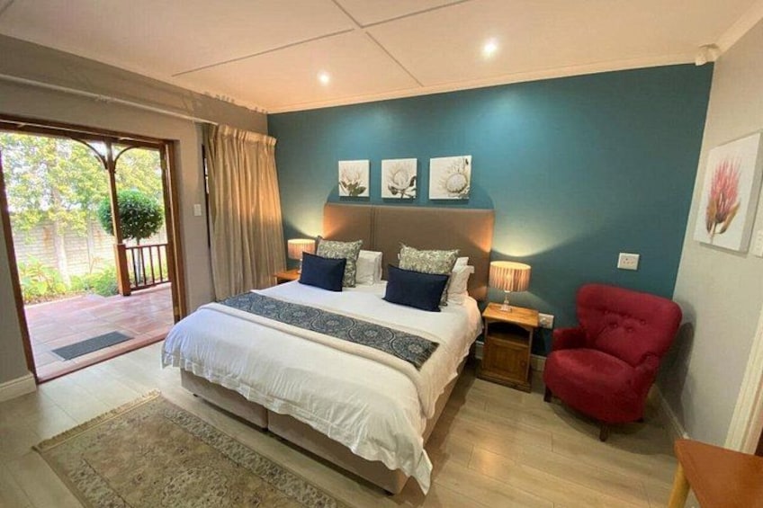 A bedroom with a large bed, a red armchair, and artwork on the walls. 3