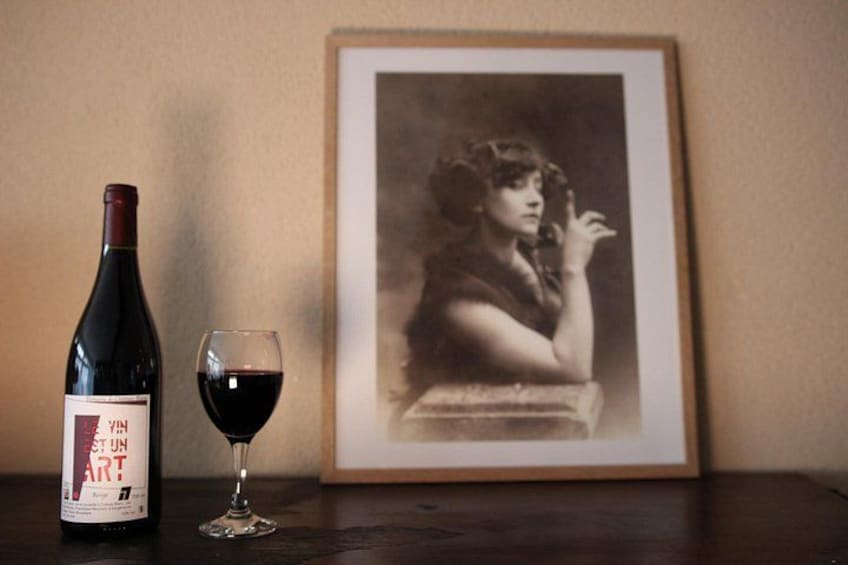 Una botella de vino, una copa de vino y una fotografía enmarcada sobre una mesa. 5