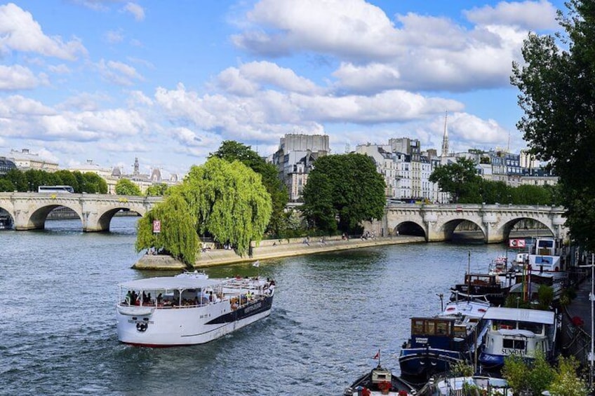 Une rivière avec un bateau, un arbre, un pont et des bâtiments en arrière-plan. 2
