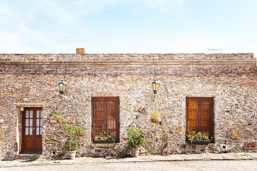 A stone building with three wooden doors and windows, each with a hanging lantern. 2