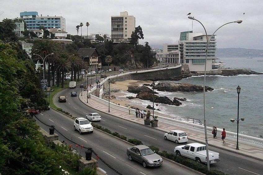 Una carretera costera con vehículos, una playa y edificios al fondo. 5