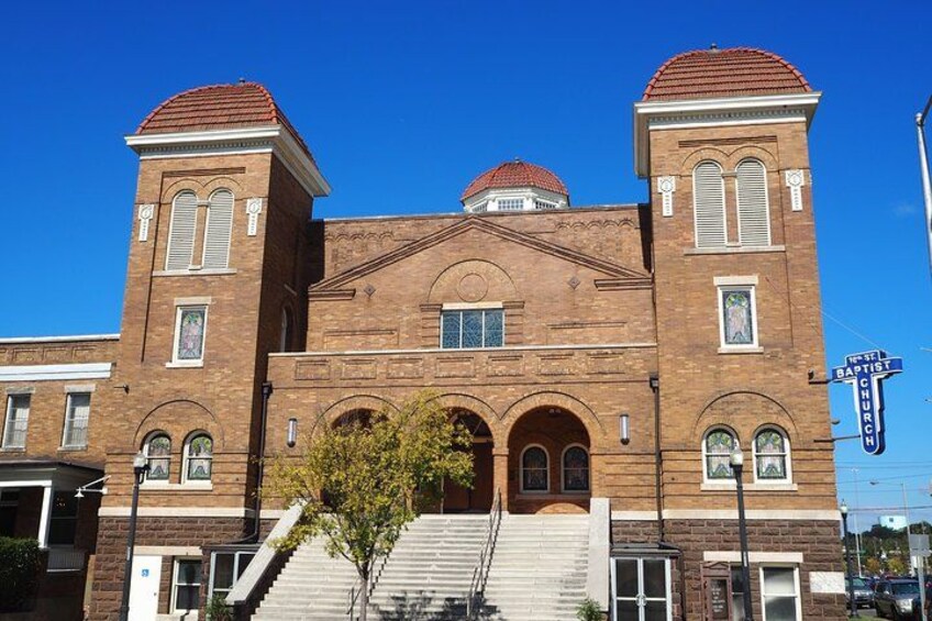 A large brick building with two towers, arched windows, and a staircase leading to the entrance. 1