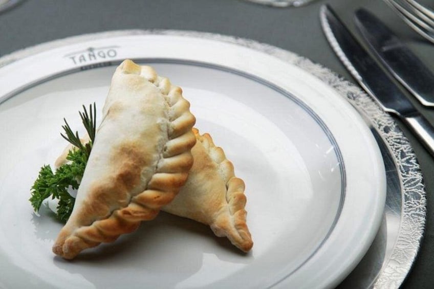 Un plato con dos pasteles dorados sobre una vajilla blanca con detalles de encaje. 3