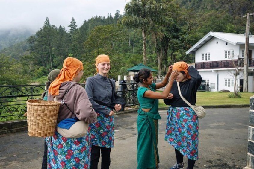 Cuatro personas con vestimenta tradicional de pie en una carretera, con una casa y árboles al fondo. 5
