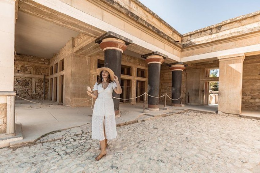A person in a white dress standing in an ancient building with columns and stone walls. 4