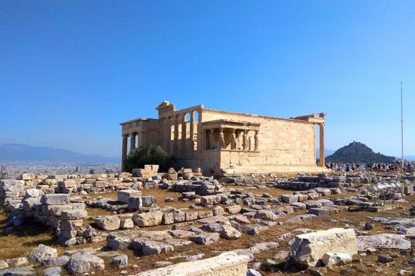 Ancient ruins with columns and a large stone structure, surrounded by scattered stones and a clear sky. 1
