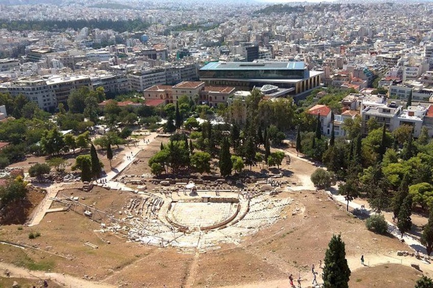 An ancient amphitheater surrounded by trees and modern buildings. 3