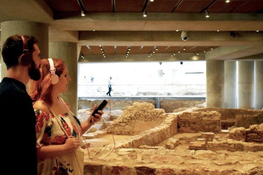 An indoor archaeological site with stone ruins and visitors observing. 4