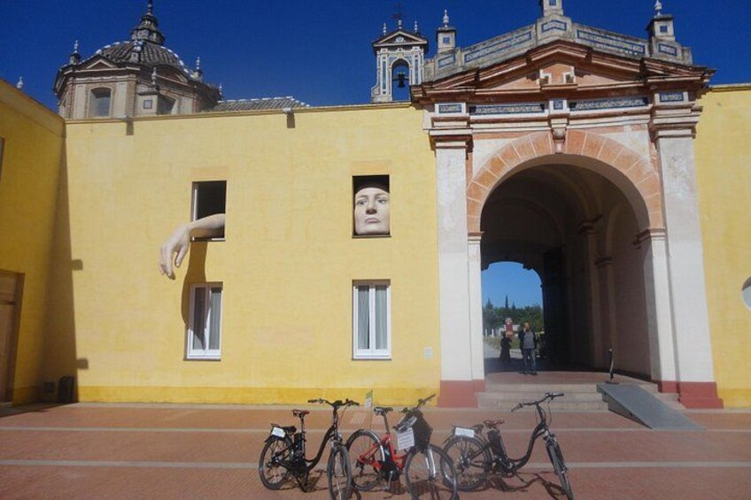 A yellow building with a large archway, bicycles parked in front, and a clear blue sky. 3