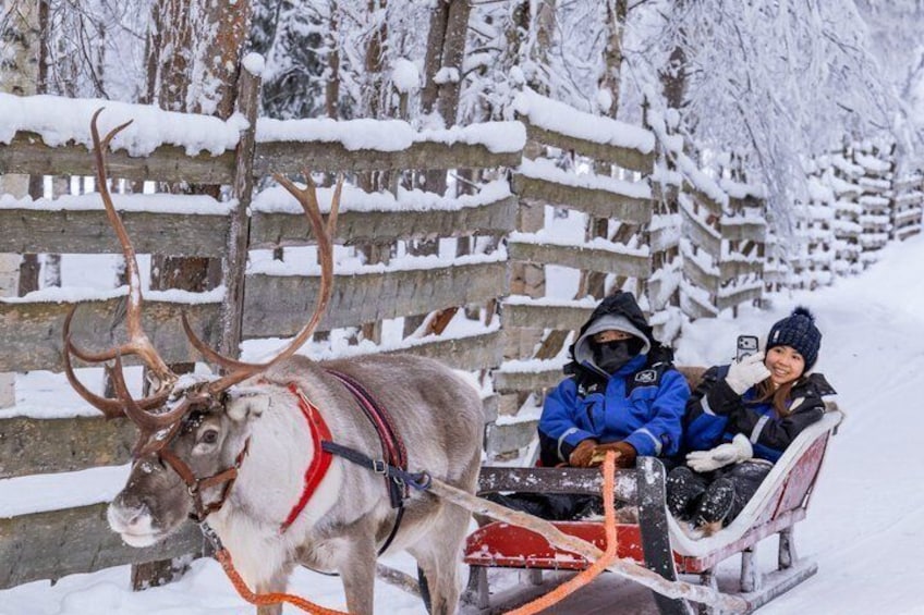 Ein Rentier zieht einen Schlitten mit zwei Personen in Winterkleidung. 5