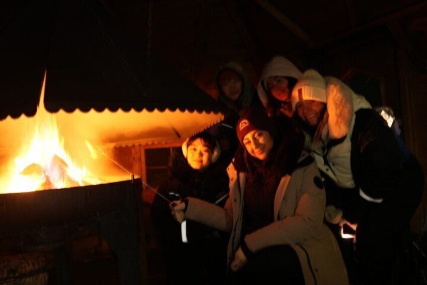 A group of people gathered around a fire in a rustic setting. 2