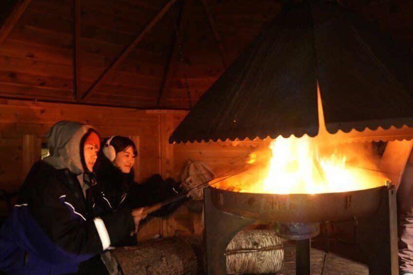 Two people inside a wooden cabin with a wood stove. 3