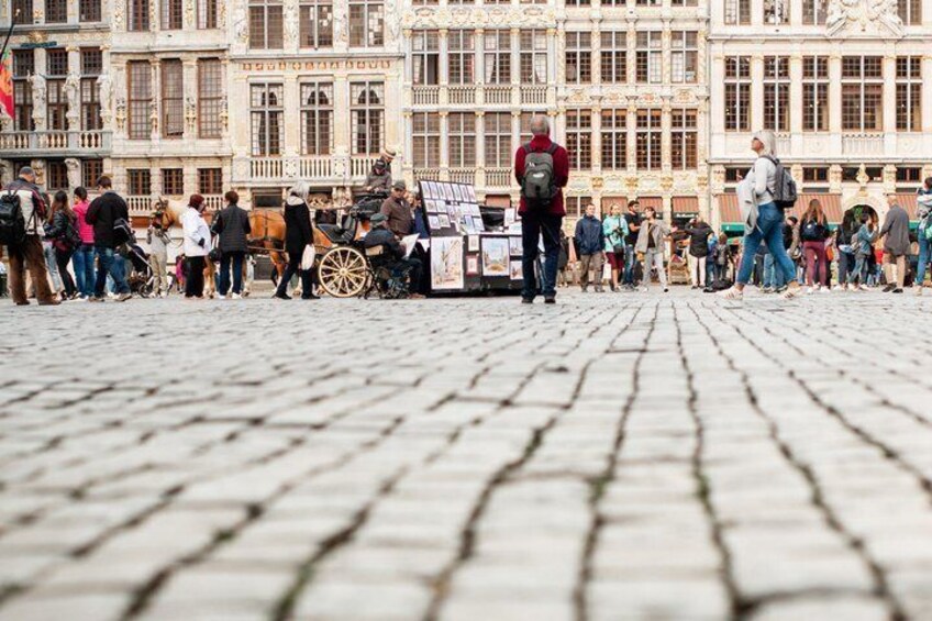 A cobblestone street with people, a horse-drawn carriage, and historic buildings. 2