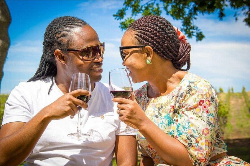Two people toasting with wine glasses in a vineyard. 5
