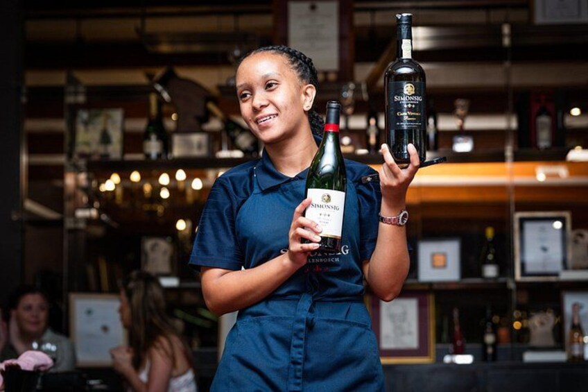A person holding a bottle of wine with a label. 3