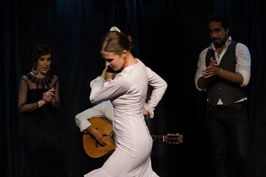 A woman in a white dress dancing, a man in a vest and shirt, and another woman in a black dress with a guitar. 5