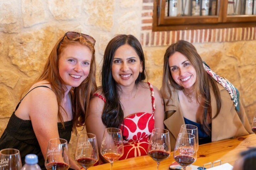 Trois femmes sont assises à une table, devant des verres à vin. 5