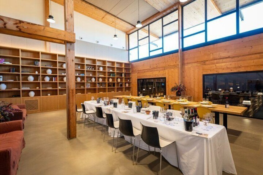 Un espace repas avec de longues tables, des chaises et un mur en bois doté d’étagères. 5