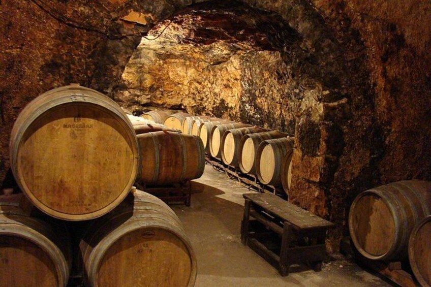 Botti di legno in una cantina scarsamente illuminata con pareti in pietra. 4