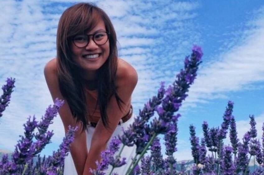 A person in a white swimsuit surrounded by purple flowers. 4