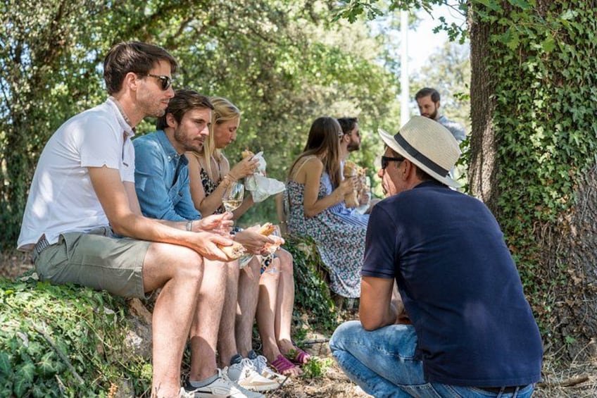 Un groupe de personnes est assis sur un banc dans un endroit boisé et discute. 2