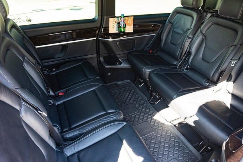 A vehicle interior with black leather seats, a center console, and a rear view mirror. 2