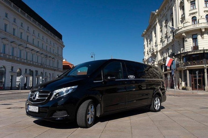 A black van parked on a paved street with buildings in the background. 5