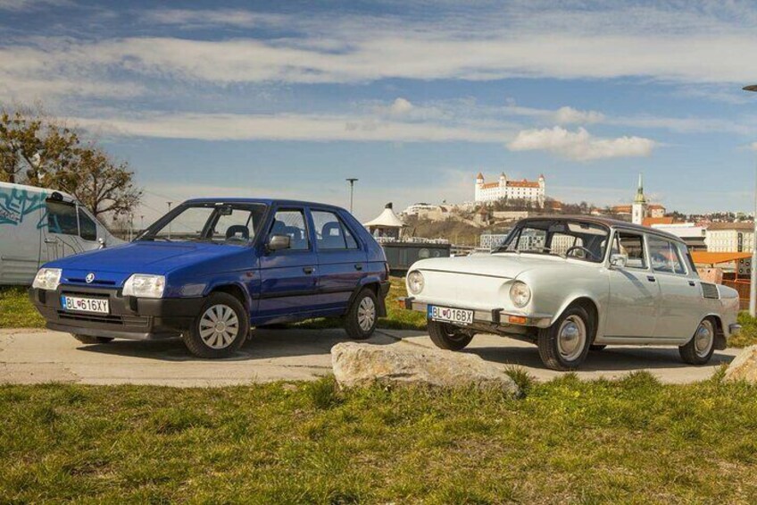 Dos autos antiguos estacionados en un césped, con un castillo al fondo. 1