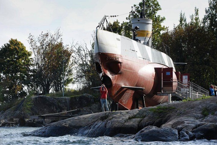 A large shipwreck on rocky shore with people standing nearby. 2