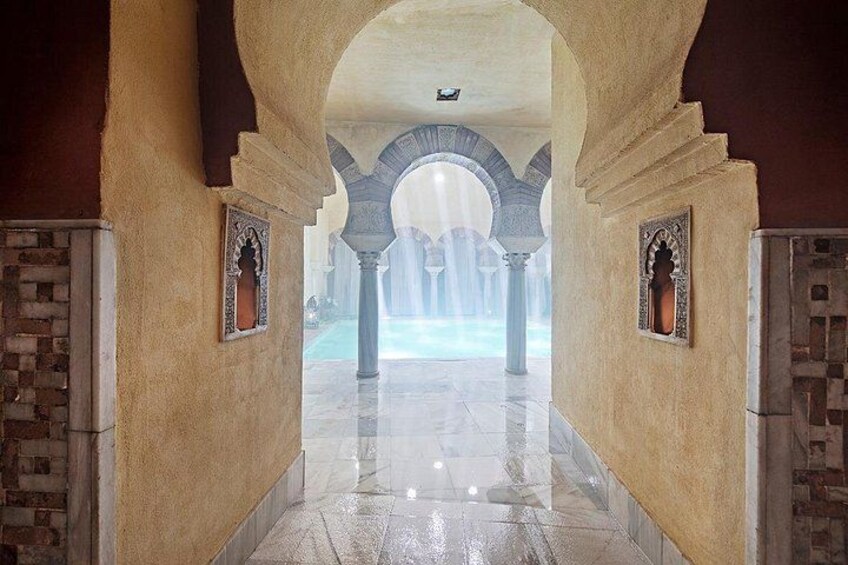 A corridor with arches, tiled walls, and a reflective floor. 2