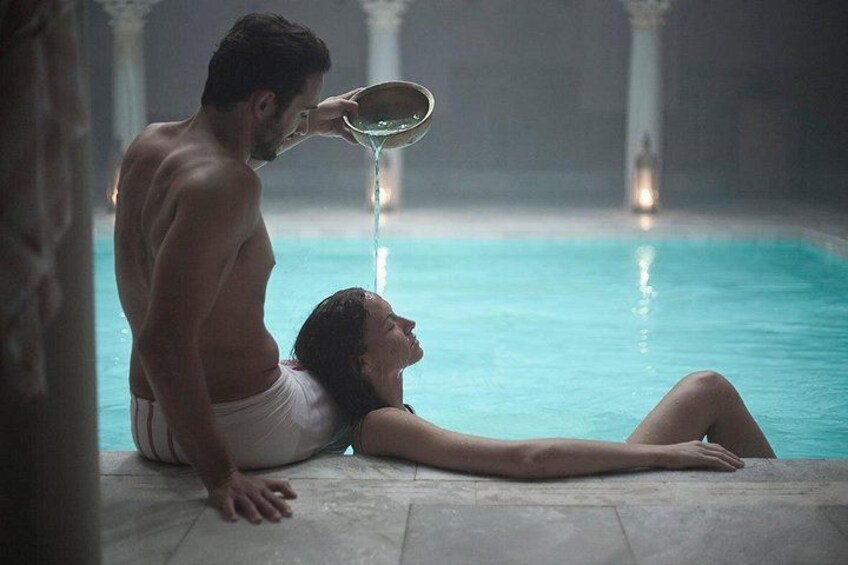 A person pouring water into another person's mouth by a pool. 3
