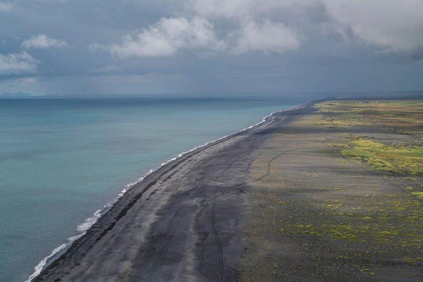 Un paisaje costero con playa, océano y cielo nublado. 4