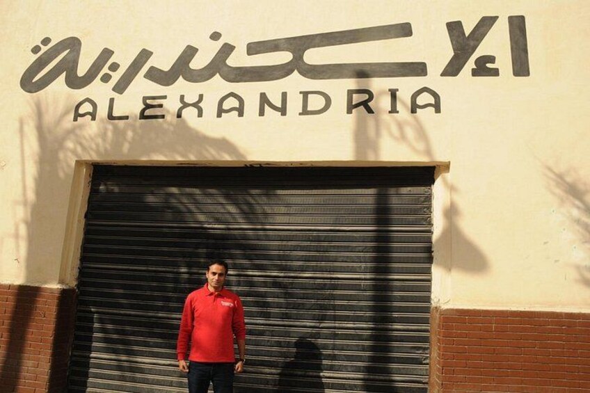 A person standing in front of a closed garage door with the sign 'ALEXANDRIA' above it. 3