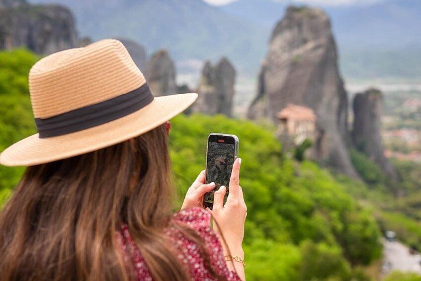 Une personne prend une photo avec un téléphone intelligent d’un paysage composé de feuillage verdoyant et de formations rocheuses. 5