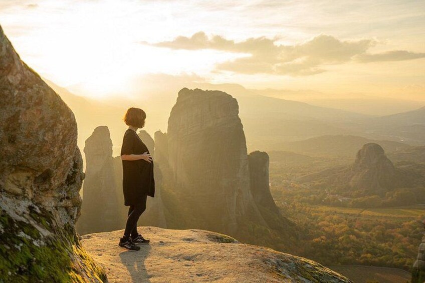 A person standing on a rock with a mountainous landscape in the background. 4