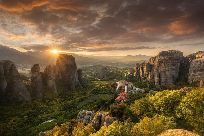 A mountainous landscape with rock formations, a village, and a sunset. 1