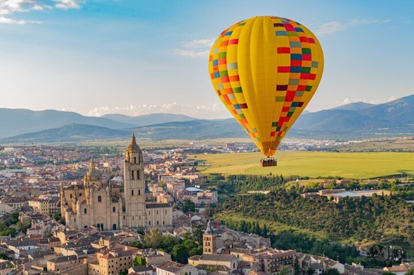 A cityscape with a prominent cathedral and a colorful hot air balloon in the sky. 1