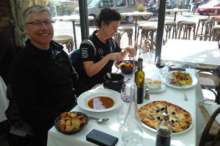Two people dining at a restaurant with a pizza and various dishes on the table. 4